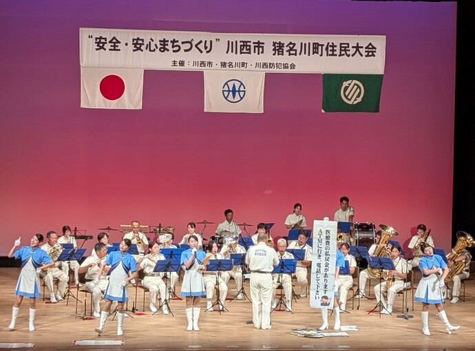 住民大会の舞台で県警音楽隊が演奏している写真