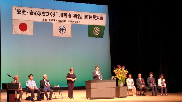 住民大会の舞台で挨拶している写真