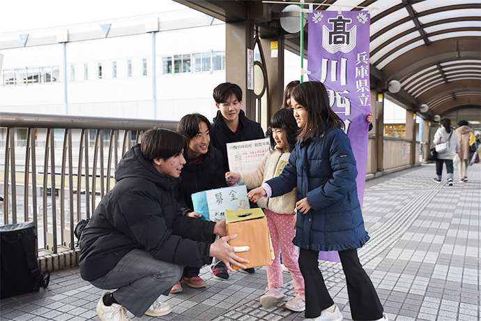 募金活動をする高校生と募金する子どもの写真